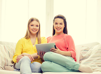 Image showing two smiling teenage girls with tablet pc at home