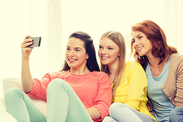 Image showing smiling teenage girls with smartphone at home