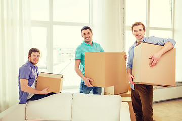 Image showing smiling male friends carrying boxes at new place