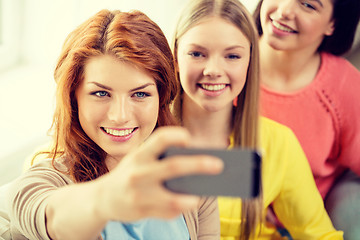 Image showing smiling teenage girls with smartphone at home