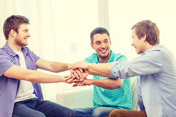 Image showing smiling male friends with hands together at home