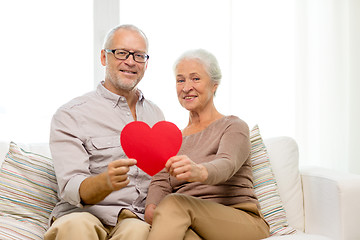 Image showing happy senior couple with red heart shape at home