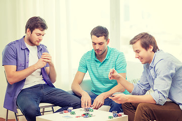 Image showing happy three male friends playing poker at home