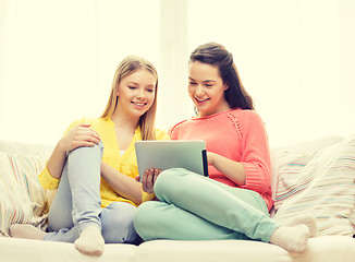 Image showing two smiling teenage girls with tablet pc at home