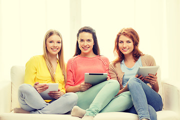 Image showing three smiling teenage girls with tablet pc at home