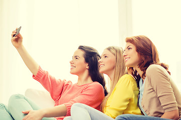 Image showing smiling teenage girls with smartphone at home