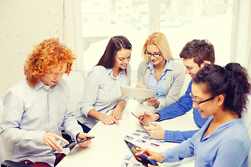 Image showing smiling team with table pc and papers working