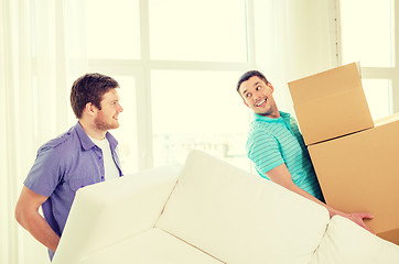 Image showing smiling friends with sofa and boxes at new home