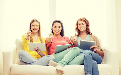 Image showing three smiling teenage girls with tablet pc at home