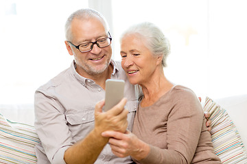 Image showing happy senior couple with smartphone at home