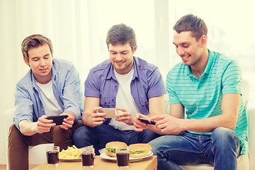 Image showing smiling friends taking picture of food at home