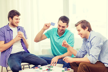 Image showing happy three male friends playing poker at home