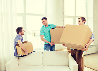 Image showing smiling male friends carrying boxes at new place