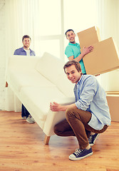 Image showing smiling friends with sofa and boxes at new home