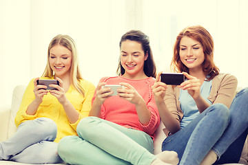 Image showing smiling teenage girls with smartphones at home