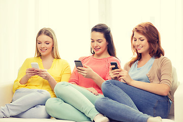Image showing smiling teenage girls with smartphones at home
