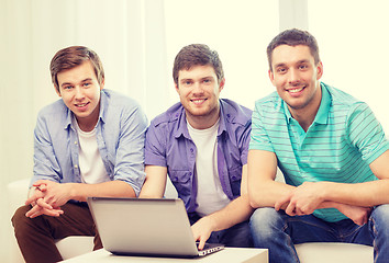 Image showing smiling friends with laptop computer at home