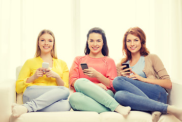 Image showing smiling teenage girls with smartphones at home