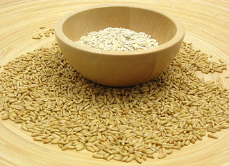 Image showing Wooden bowl with oat flakes and corn on bamboo plate