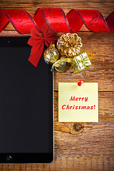 Image showing tablet pc with christmas decorations on wooden background