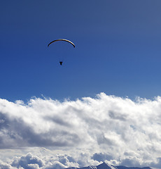 Image showing Silhouette of paraglider and blue sun sky