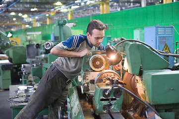 Image showing Young turner adjusts machine