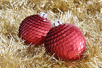 Image showing Two red Christmas baubles on golden tinsel