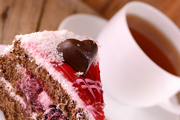 Image showing Piece of cake with chocolate heart on wooden background