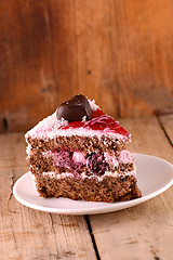 Image showing Piece of cake with chocolate heart on wooden background