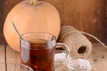 Image showing Cup of tea with autumn leaves with pumpkin on wooden table