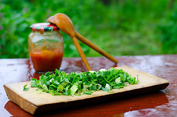 Image showing Chopped green onions on a cutting Board, on the background of tw