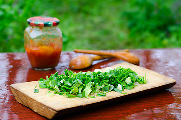 Image showing Still life of sliced green onions on a cutting Board, wooden spo