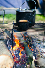 Image showing Tourist boiler with food and a mug with water on a fire