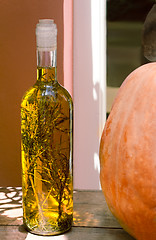Image showing Still life: a bottle of olive oil , along with herbs, and pumpki