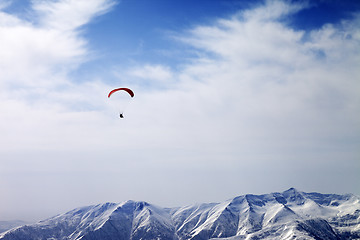 Image showing Paraglider silhouette of mountains in windy sky