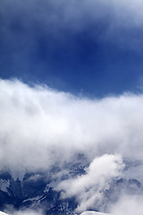 Image showing Snowy mountains in clouds at sun day