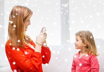 Image showing smiling mother and daughter with camera