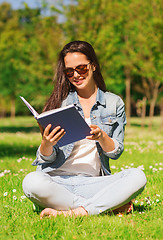 Image showing smiling young girl with book sitting in park