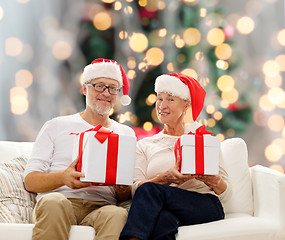 Image showing happy senior couple in santa hats with gift boxes