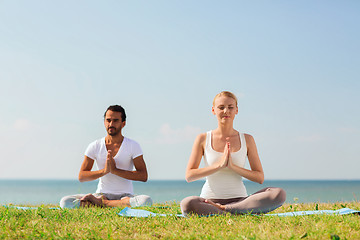 Image showing smiling couple making yoga exercises outdoors