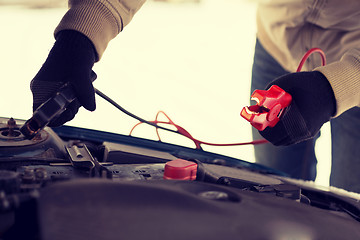 Image showing closeup of man under bonnet with starter cables