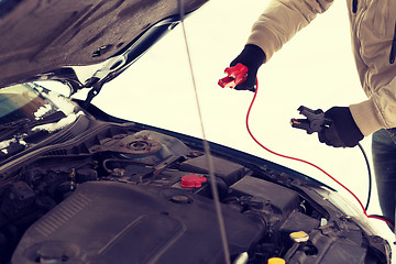 Image showing closeup of man under bonnet with starter cables