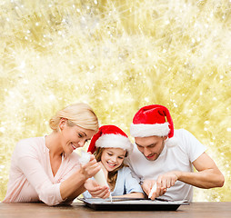 Image showing happy family in santa helper hats cooking