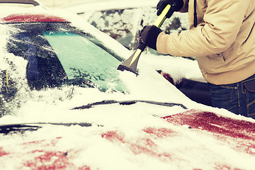 Image showing closeup of man scraping ice from car