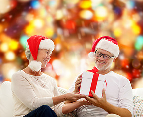 Image showing happy senior couple in santa hats with gift box