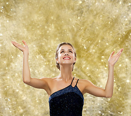 Image showing smiling woman raising hands and looking up