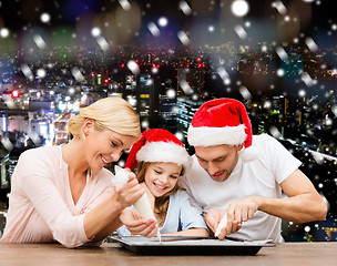 Image showing happy family in santa helper hats cooking