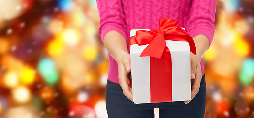 Image showing close up of woman in pink sweater holding gift box