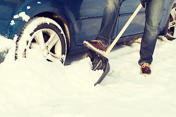 Image showing closeup of man digging up stuck in snow car