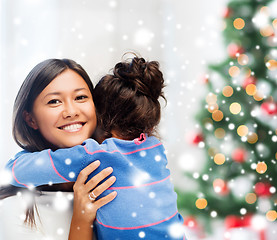 Image showing smiling little girl and mother hugging indoors